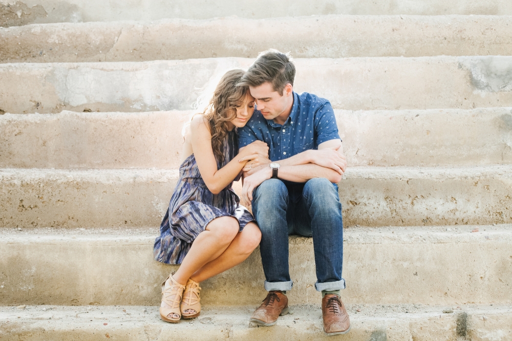 The couple cuddling on the concrete steps. 