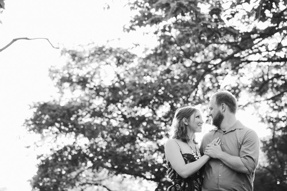 A beautiful black and white photo of the couple by trees. 