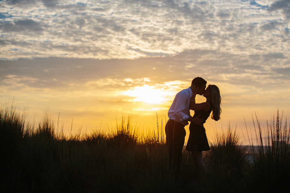 The couple kissing during sunset. 