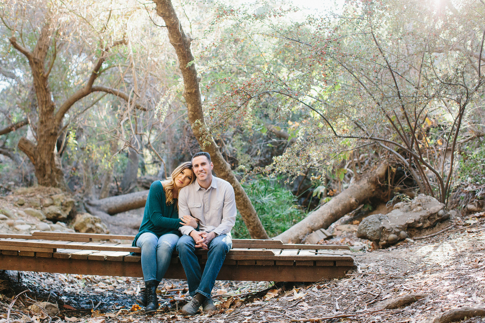 The couple sitting on a bridge. 