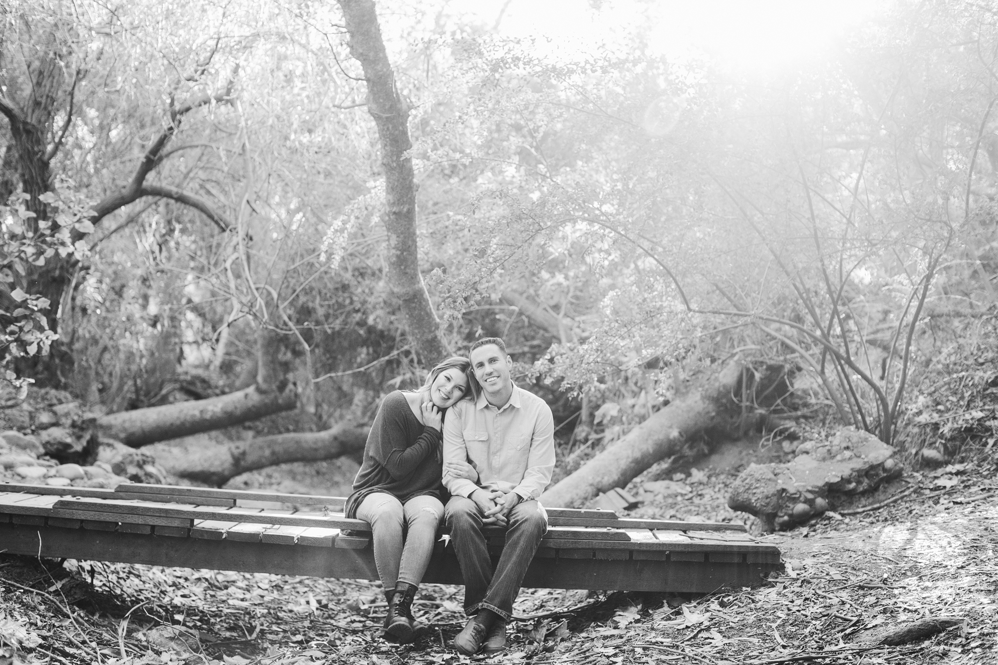 A cute black and white photo of the couple on a bridge. 