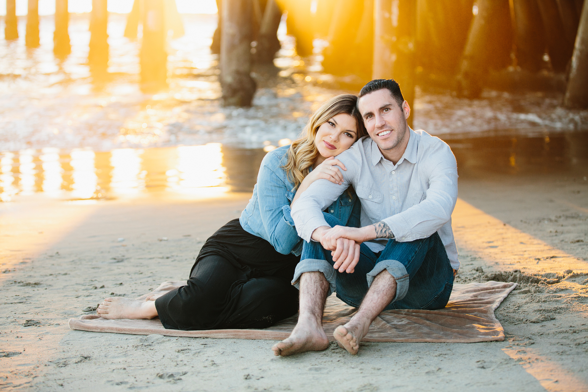 The couple sitting together on a blanket. 