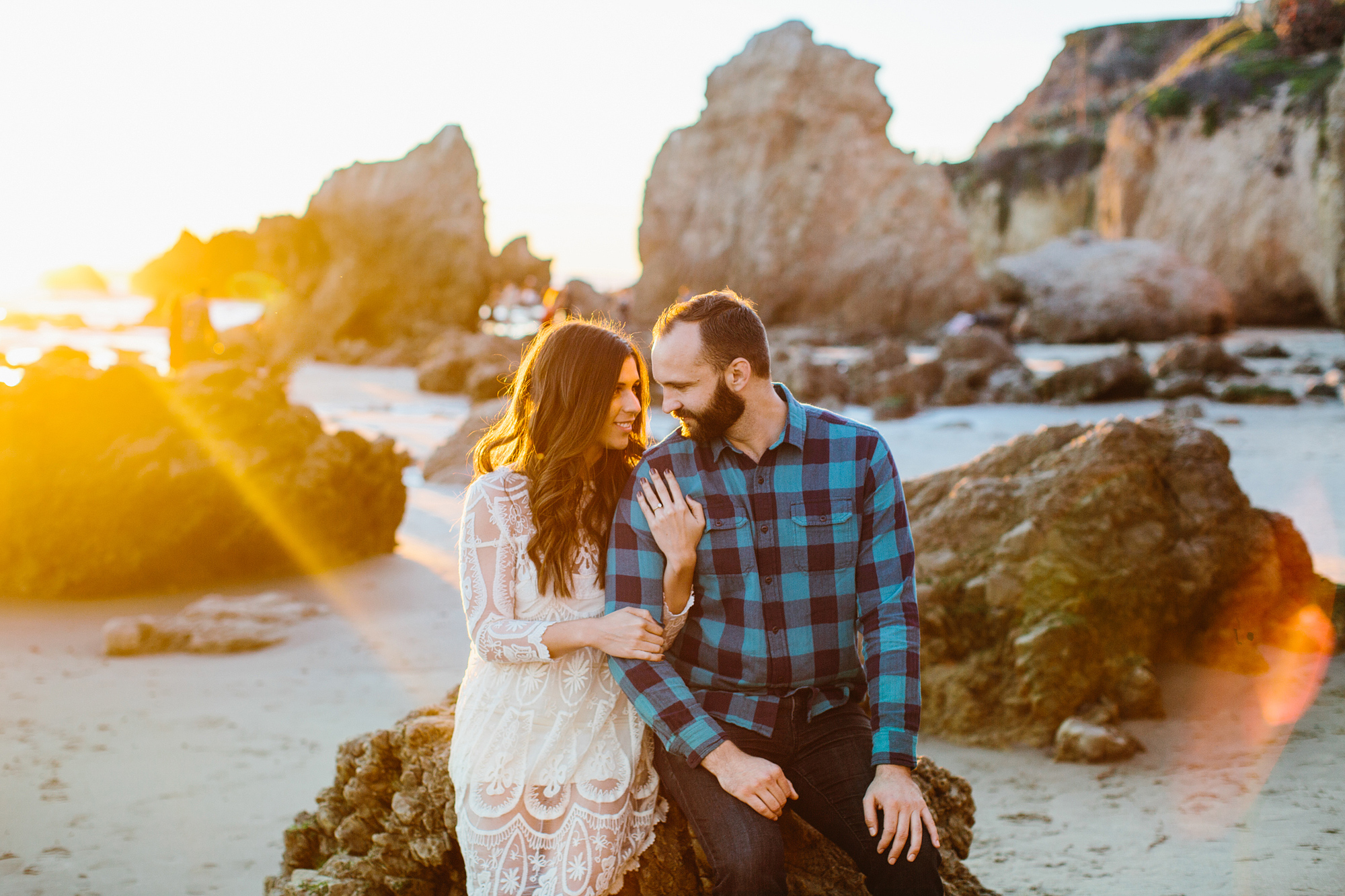 The couple sitting on a rock at sunset. 