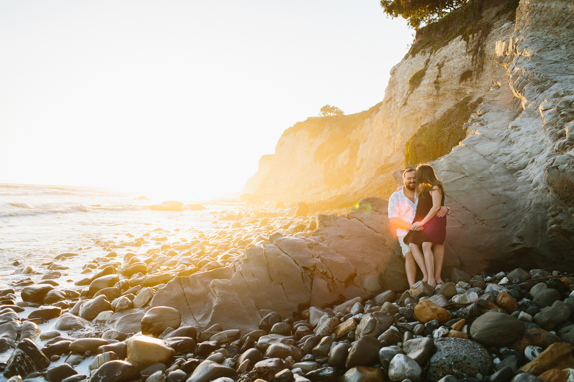 A gorgeous photo of the couple sitting on a large rock. 