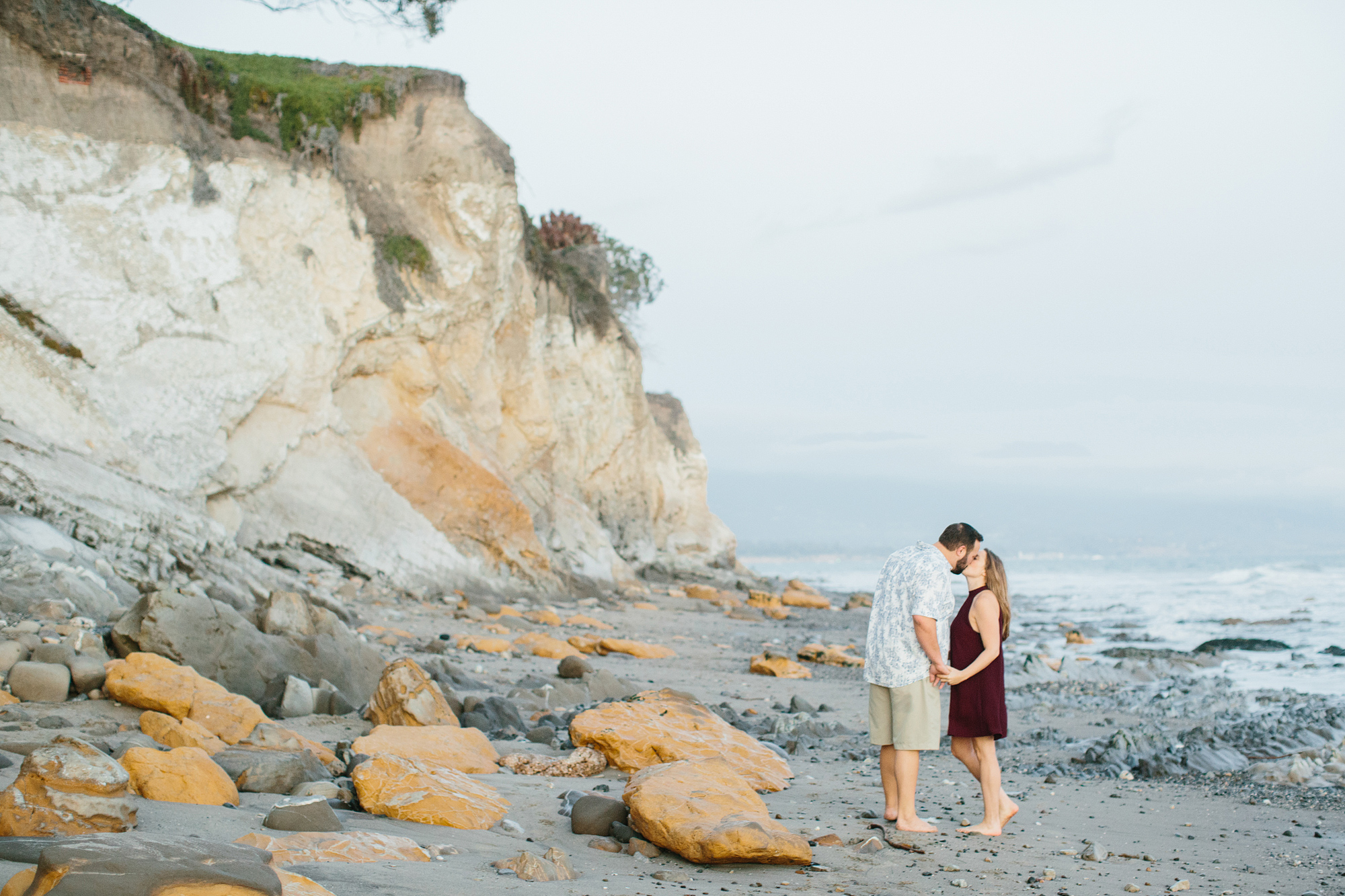 The couple on the beach near the cliffside. 