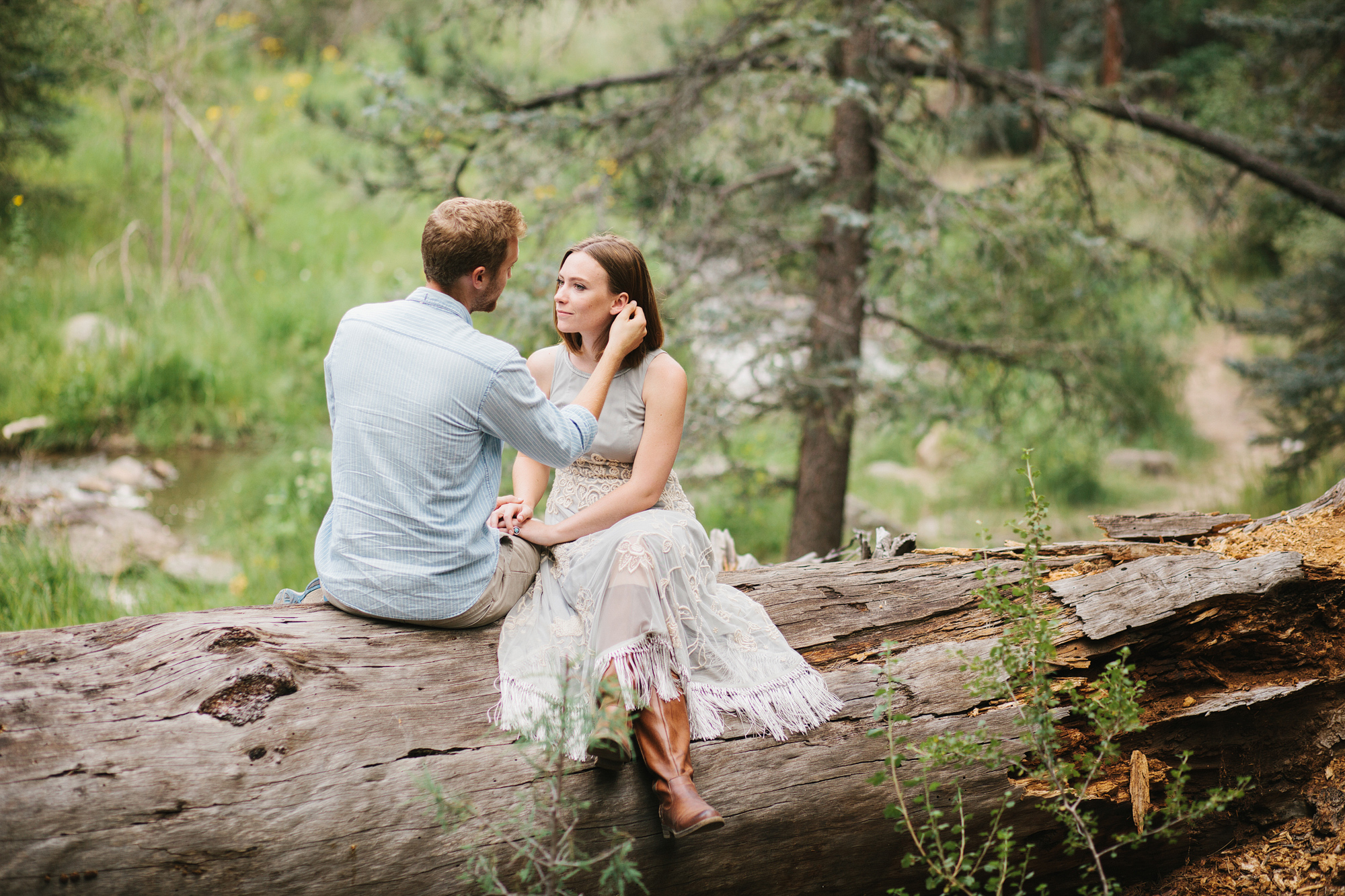 The couple sitting on a fallen tree. 